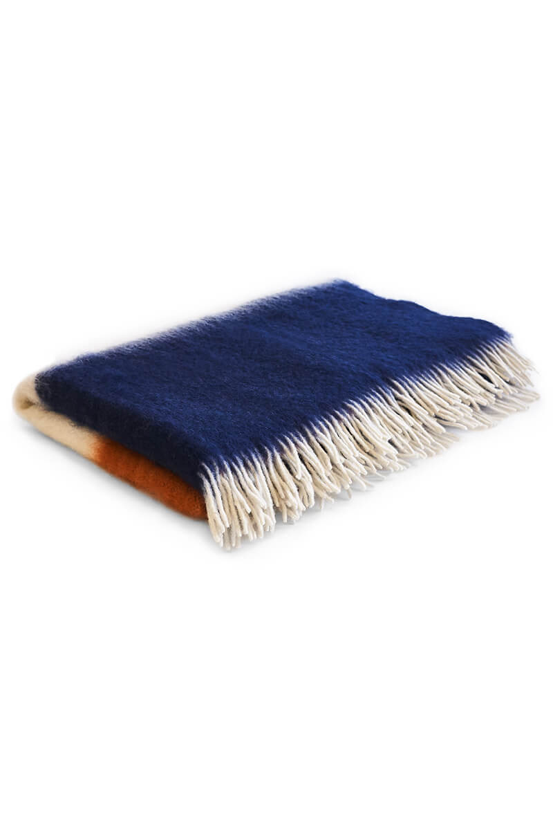 Pink, orange, white and navy mohair blanket resting on white background