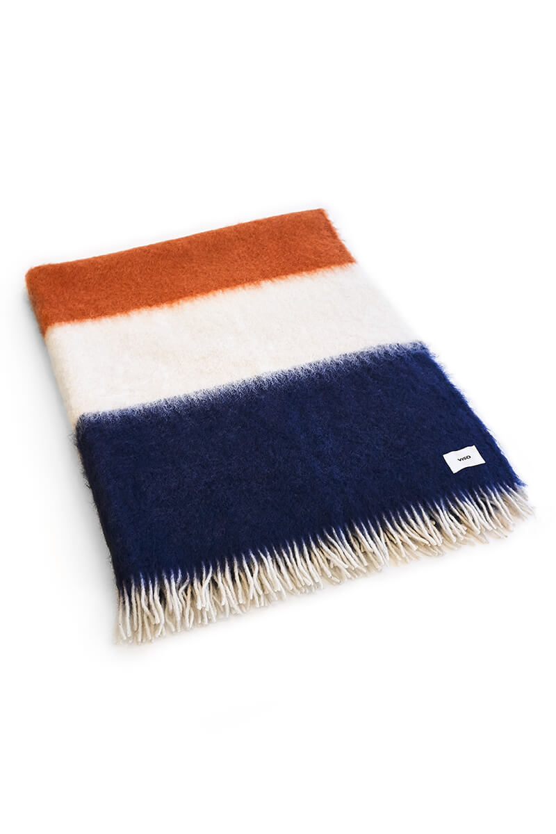 Pink, orange, white and navy mohair blanket resting on white background